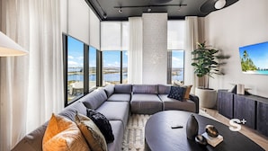 A modern living room with a sectional sofa, a round coffee table, and a large window offering a city view. - Chic Downtown Studio in Miami (Miami)