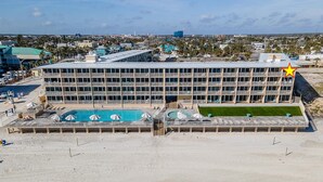 A multi-story hotel with a rooftop pool area and a large building in the background. - Daytona Inn Beach Resort 409 (Daytona Beach)
