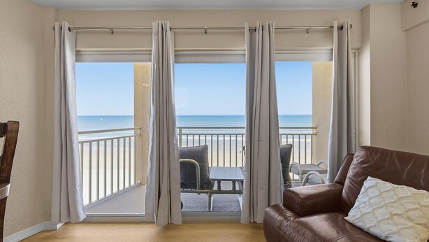 A room with a balcony, a brown leather sofa, and a view of the sea. - Daytona Inn Beach Resort 409 (Daytona Beach)