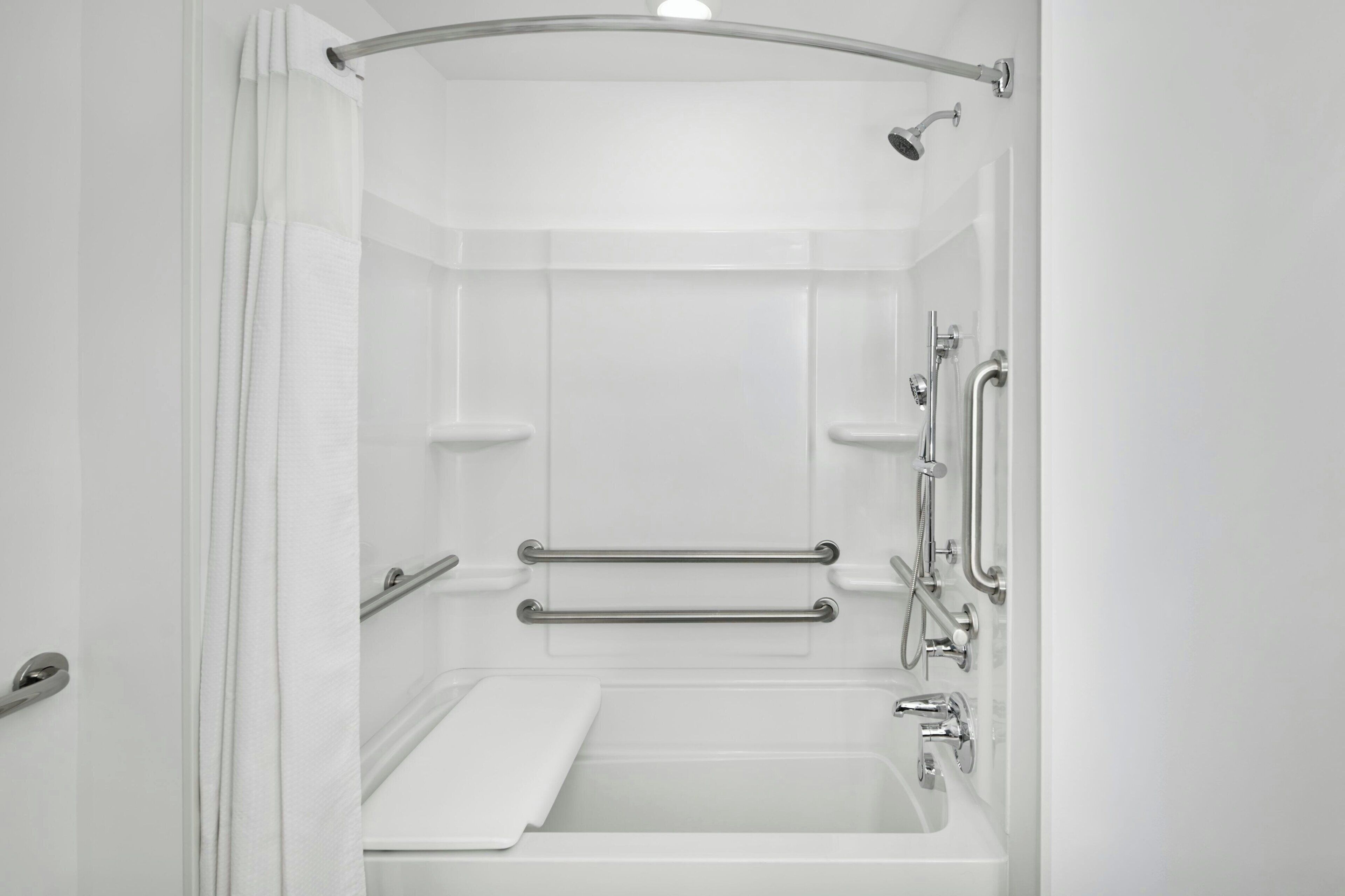 Eine moderne Dusche mit Glastür, Haltegriffen und Duschbrause.