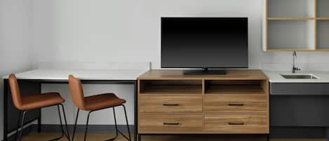 A modern room with a desk, two chairs, a TV, a sink, and a cabinet.