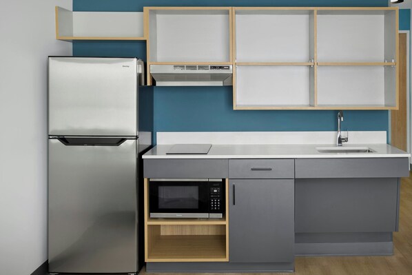 Cocina compacta con refrigerador, microondas y horno empotrado.