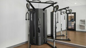Une salle de sport avec un mur recouvert de miroirs, une barre de traction et une machine de musculation.