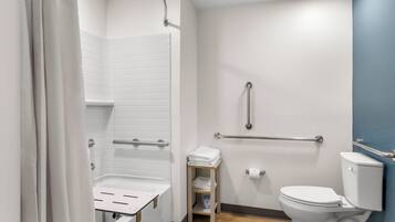 A modern bathroom with a shower, toilet, and grab bars.
