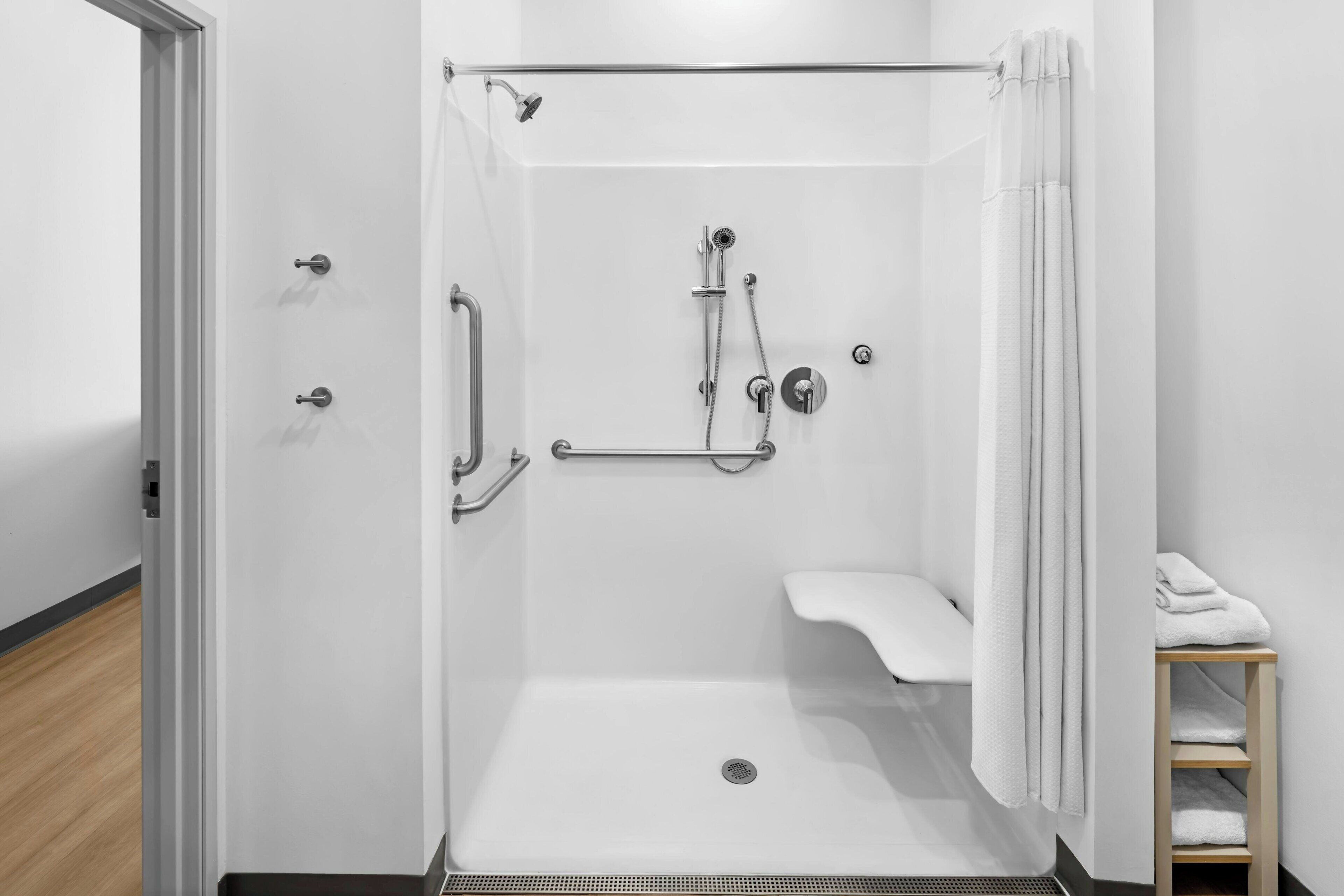 A white shower with a handheld showerhead, a handheld shower attachment, and a handheld faucet.