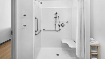 A white shower with a handheld showerhead, a handheld shower attachment, and a handheld faucet.