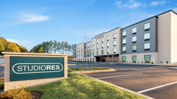 A modern building with a sign reading 'STUDIORES' and a parking lot.