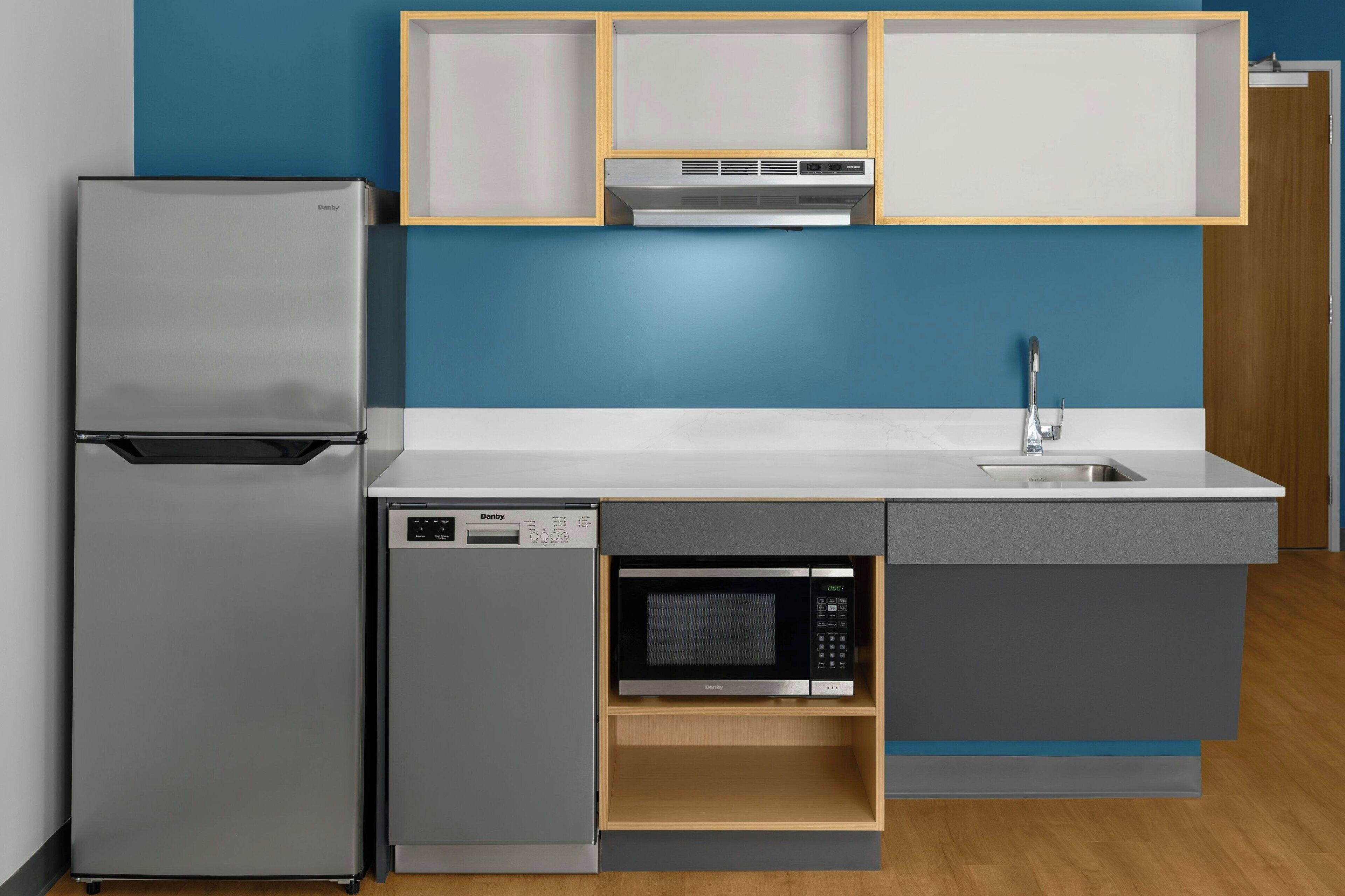 A compact kitchen with a refrigerator, dishwasher, microwave, and a built-in oven.