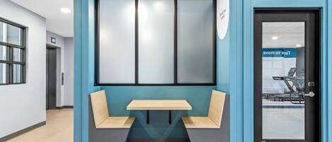 A modern waiting area with a bench, a table, and a door with a sign.