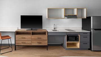 Una cocina moderna con televisor de pantalla plana, microondas integrado y refrigerador.