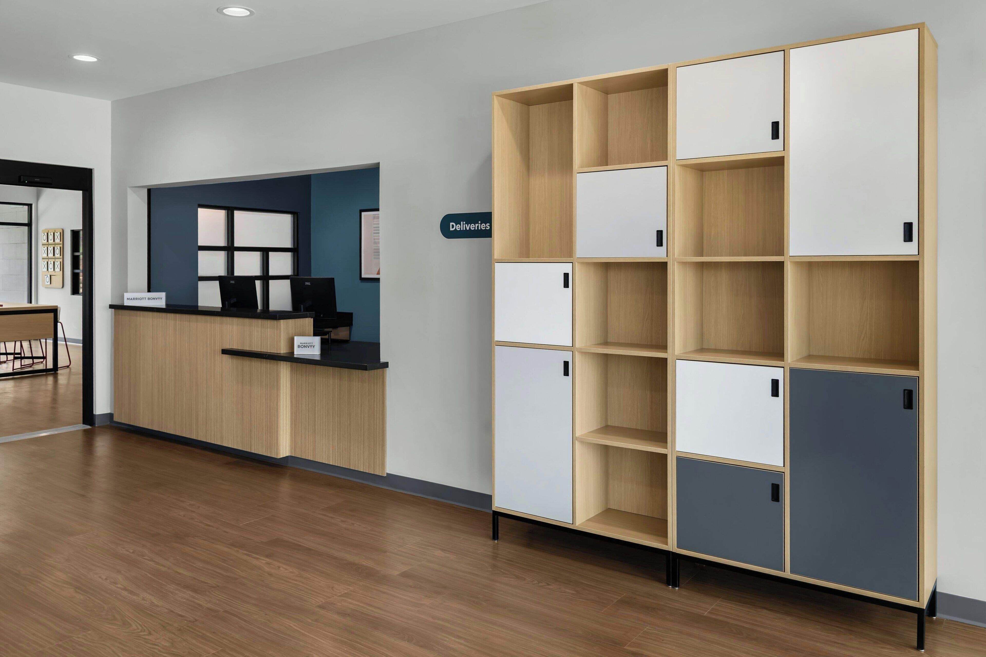 Un área de recepción con un escritorio de madera, una pared azul y un mueble de almacenamiento grande con varios compartimentos.