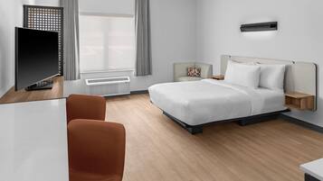 Habitación de hotel moderna con cama, escritorio, silla y ventana con cortinas.