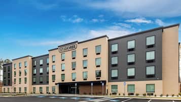 A multi-story hotel with a sign 'STUDIOS,' parking spaces, and a clear sky.