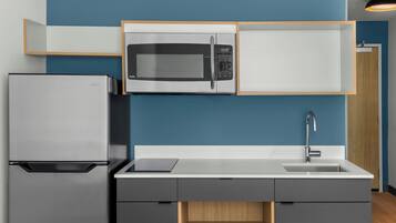 Une cuisine moderne équipée d’un four à micro-ondes, d’un réfrigérateur et d’un évier intégrés.