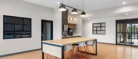 Une cuisine moderne dotée d’un îlot central, de luminaires suspendus et donnant sur l’espace repas.