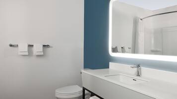 Un baño moderno con inodoro blanco, lavamanos con espejo y un perchero para toallas.