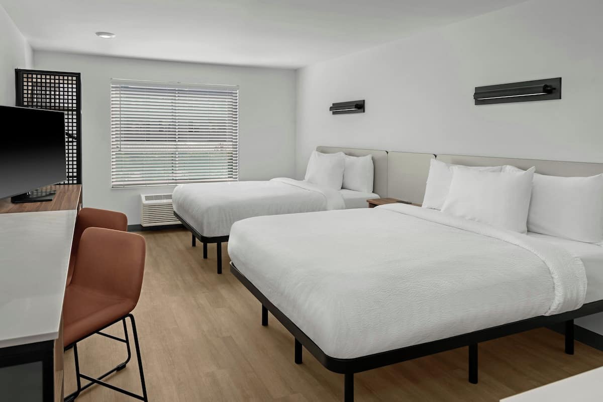 Een hotelkamer met twee bedden, een bureau, een stoel en een televisie.