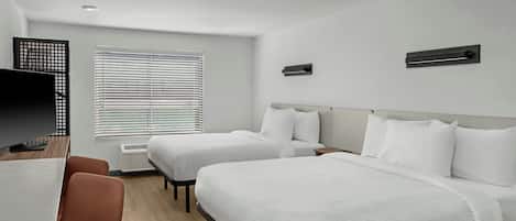 A hotel room with two beds, a desk, a chair, and a TV.
