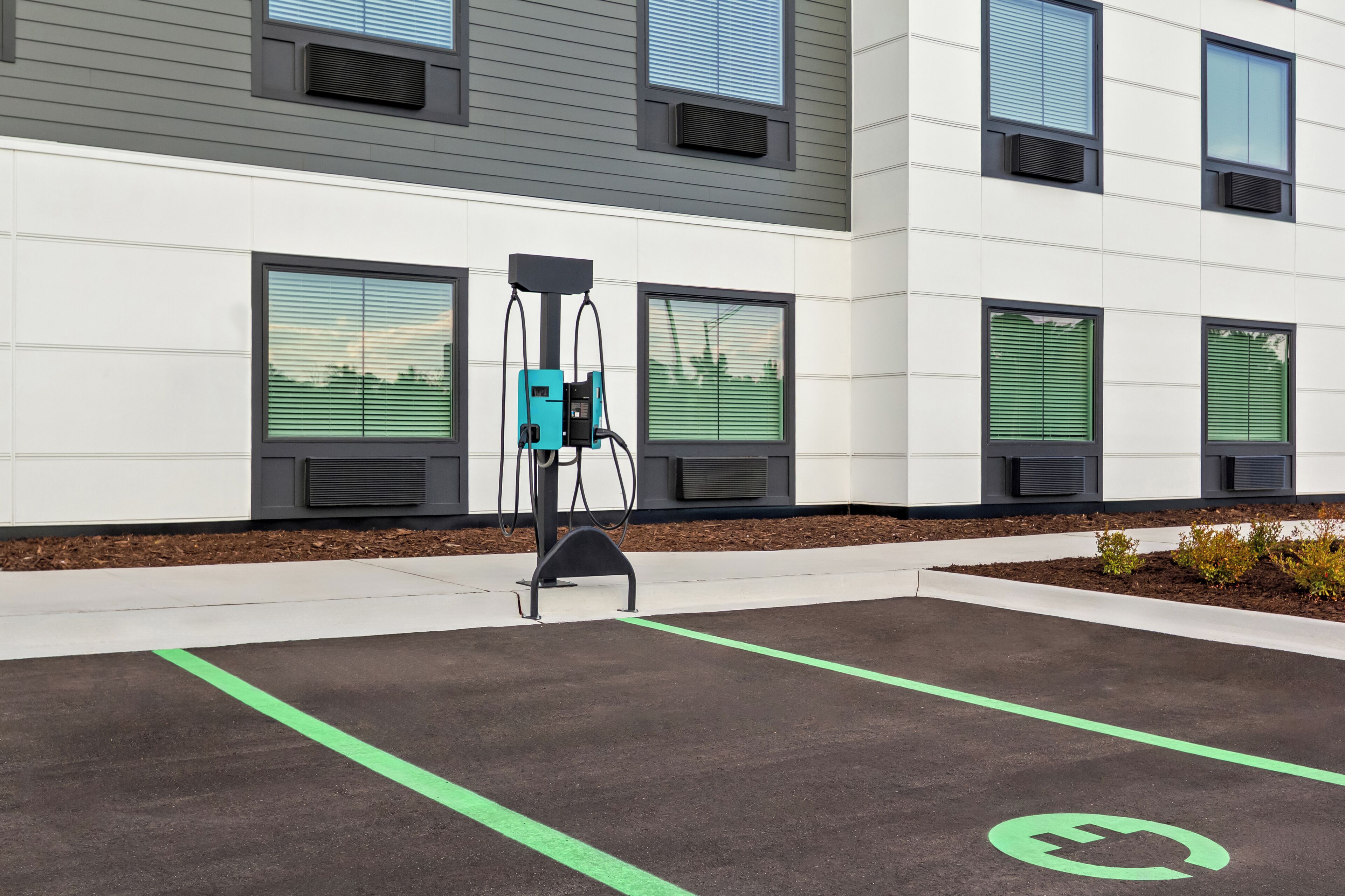 An electric vehicle charging station in a parking lot with a building in the background.