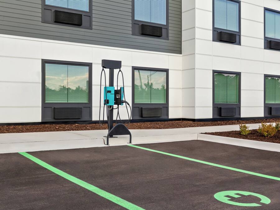 An electric vehicle charging station in a parking lot with a building in the background.