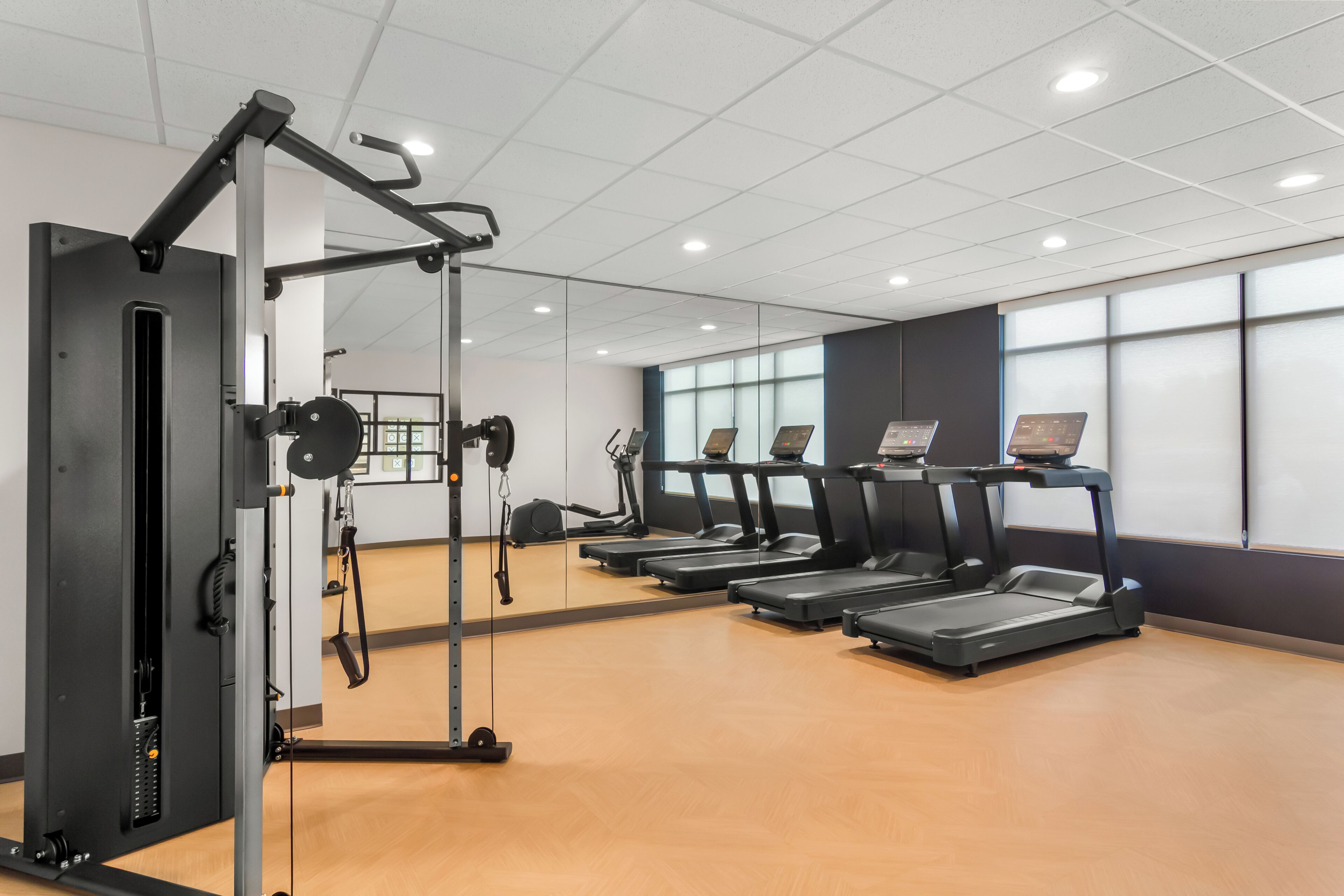 A gym with treadmills, a weight machine, and a mirror.