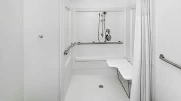 A white, accessible shower room with a grab bar, a handheld showerhead, and a handheld faucet.