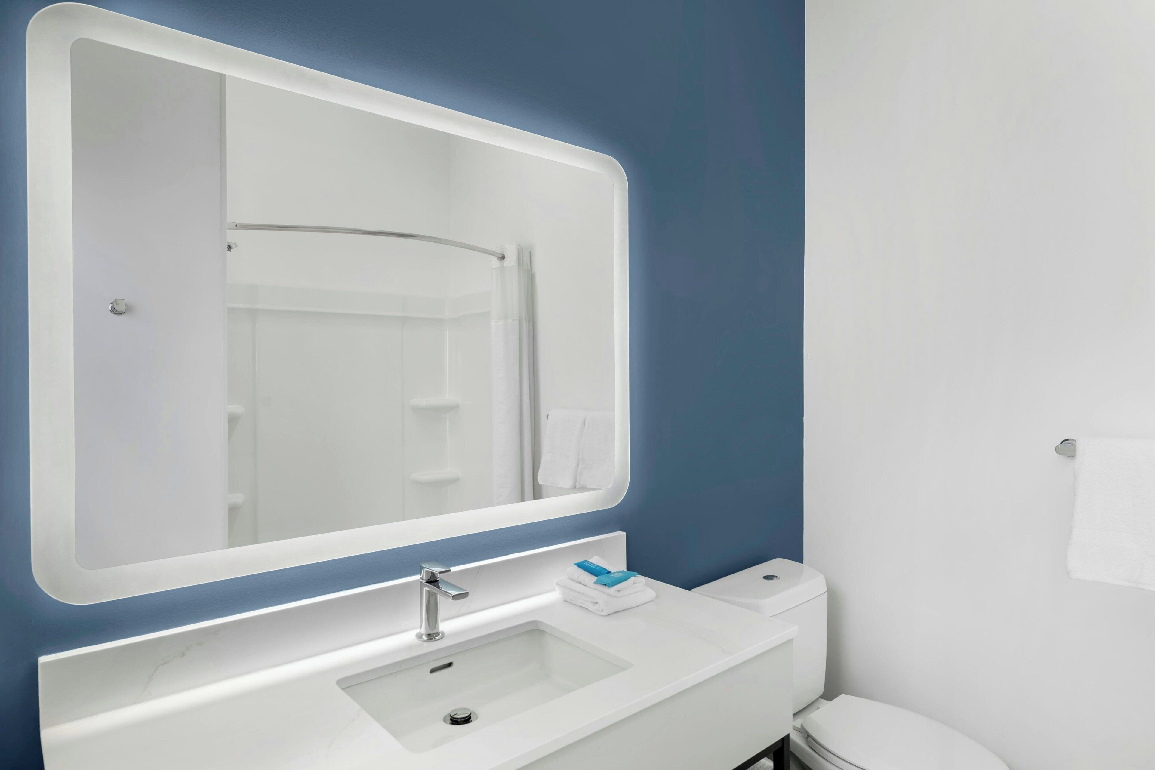 Un baño con un lavamanos blanco, un espejo y un inodoro.