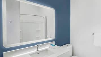 A bathroom with a white sink, a mirror, and a toilet.