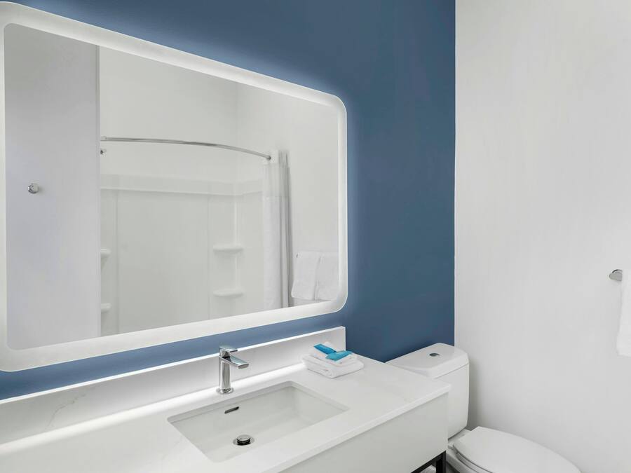 Un baño con un lavamanos blanco, un espejo y un inodoro.