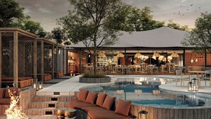 Un área de piscina al aire libre con terraza de madera, asientos y una chimenea.