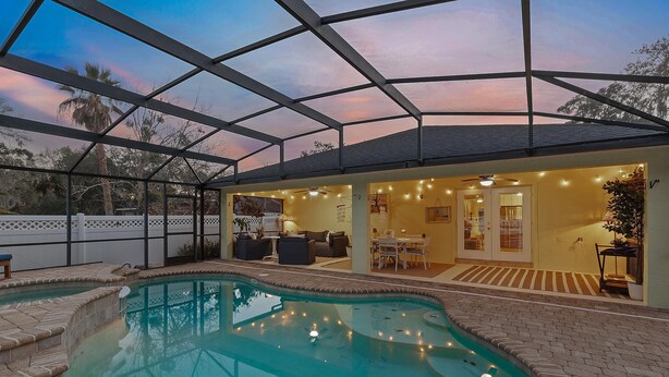 Una piscina scoperta coperta con una zona prendisole, posti a sedere e vista sul cielo.