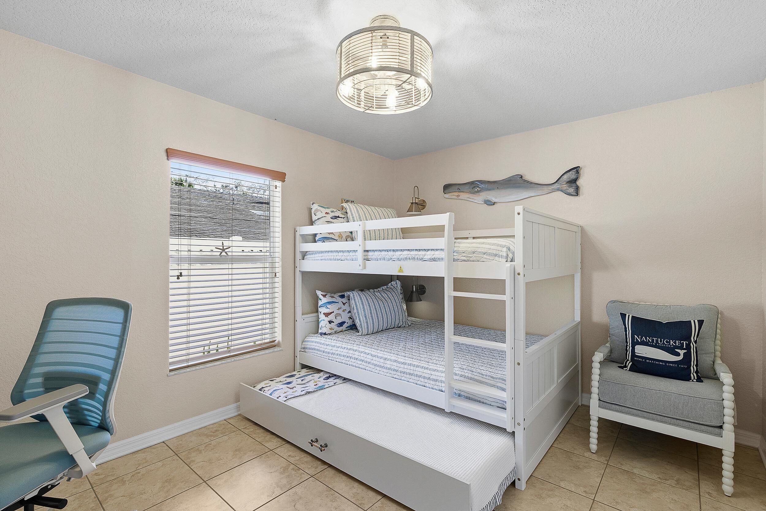 A child's bedroom with bunk beds, a desk, and a chair.