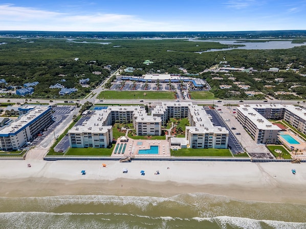 A coastal hotel with multiple buildings, a beach, and a pool area. - Castle Reef 109 (New Smyrna Beach)