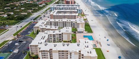 Un hotel frente a la playa con varias edificaciones, estacionamiento y acceso directo a la playa.
