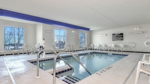 A swimming pool with clear water, surrounded by white chairs and a blue ceiling. - Cobblestone Hotel & Suites - Monte Vista (Monte Vista)