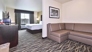 A hotel room with a bed, a sofa, a desk with a computer, a TV, and a framed picture on the wall. - Cobblestone Hotel & Suites - Monte Vista (Monte Vista)