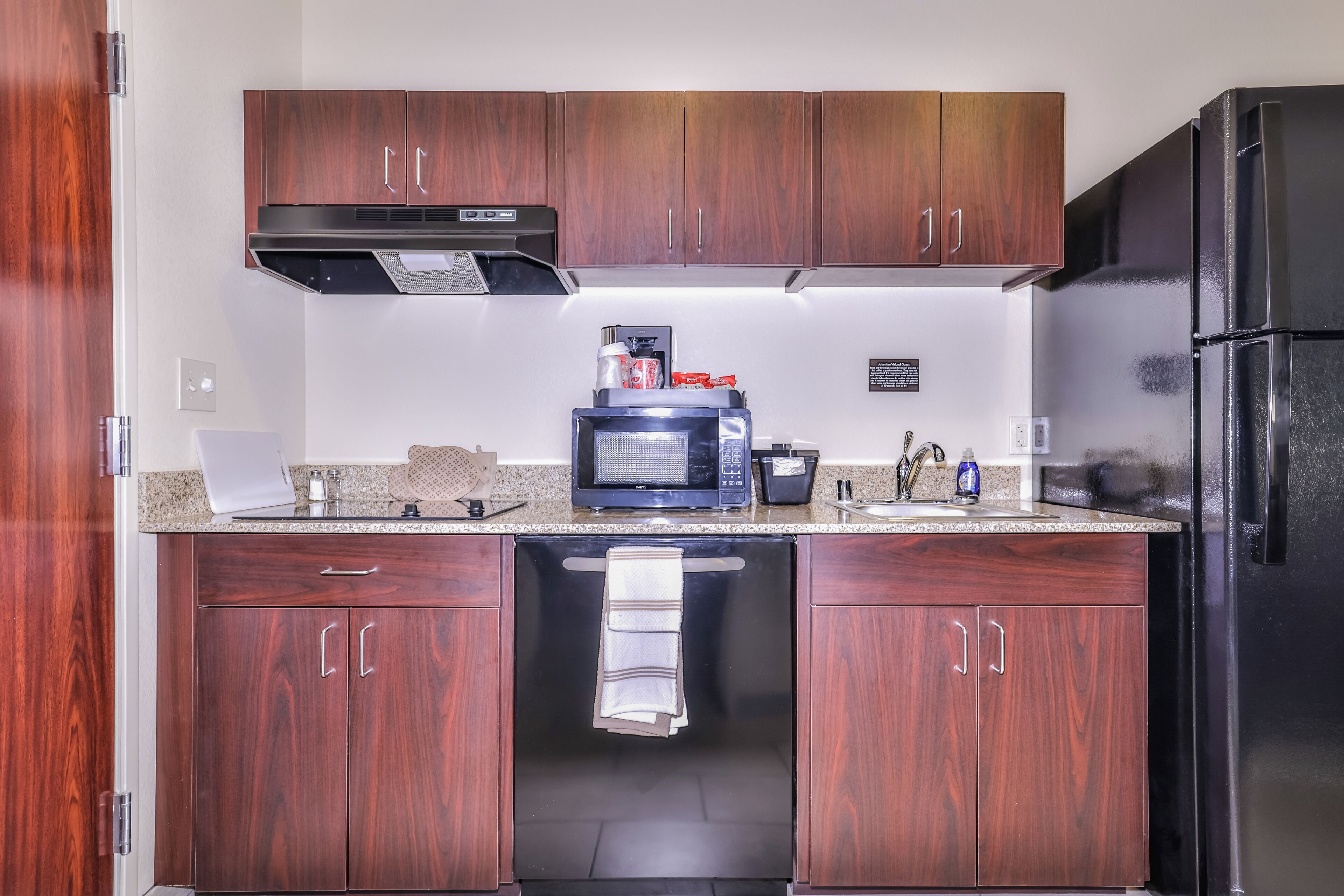 Una cucina moderna con mobili in legno, un forno a microonde integrato e un frigorifero in acciaio inossidabile.