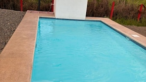 Ein rechteckiger Swimmingpool mit klarem, blauen Wasser, umgeben von einer Betonplattform und roten Sicherheitsgeländern.