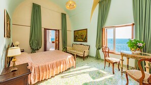 Ein Schlafzimmer mit Bett, einer Couch, einem Esstisch mit Stühlen, einer Chandelier und einem Gemälde.