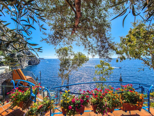 A coastal terrace with a view of the sea, stone steps, and colorful flower planters. - Villa Incanto sul Mare (Furore)