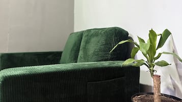 Un sofá tapizado en verde frente a una pared con dos cuadros enmarcados.