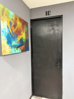 A door with a number plate, a black door, and a colorful abstract painting on the wall. - Adhoc Macro (Monterrey)