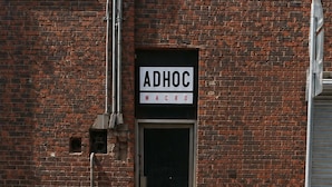 A brick building with a sign reading 'ADHOC MACRO' above a door. - Adhoc Macro (Monterrey)