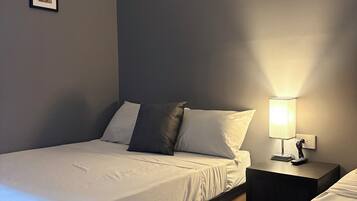 Ein Einzelbett mit Holzrahmen, ein Nachttisch mit Lampe und ein gerahmtes Bild an der Wand.