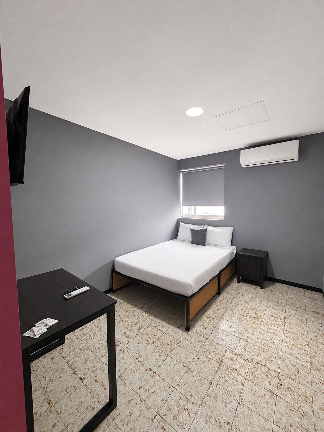 Une petite chambre moderne, équipée d’un lit, d’un bureau et d’une table de chevet.