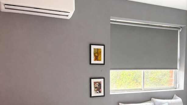 A modern bedroom with a bed, a window, and two framed pictures on the wall. - Adhoc Macro (Monterrey)