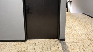 A closed door with a handle, a tiled floor, and a staircase to the right. - Adhoc Macro (Monterrey)