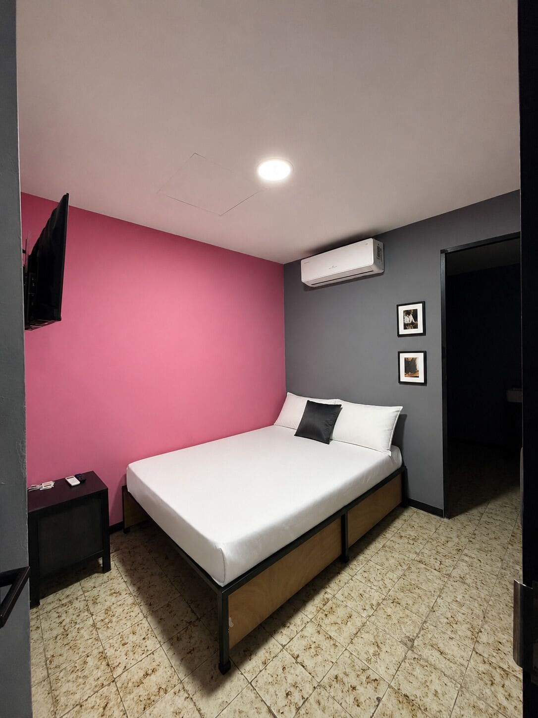 Une chambre avec un lit, une télévision, un climatiseur et une porte.