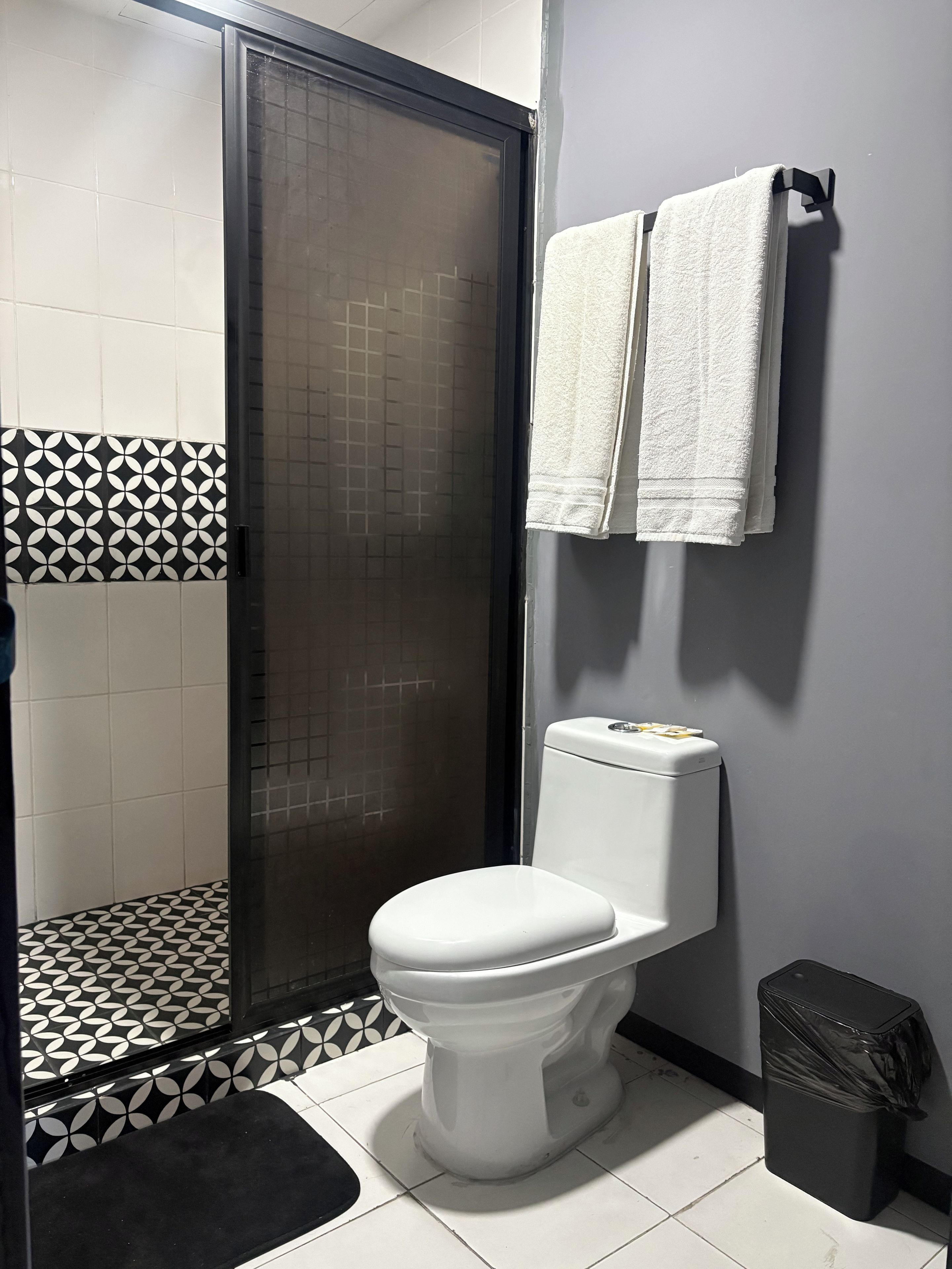 Un baño con inodoro, cabina de ducha y perchero.