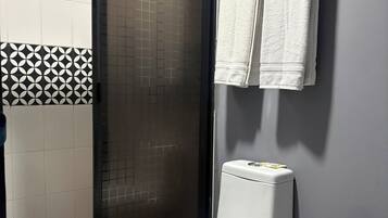 Un baño con inodoro, cabina de ducha y perchero.